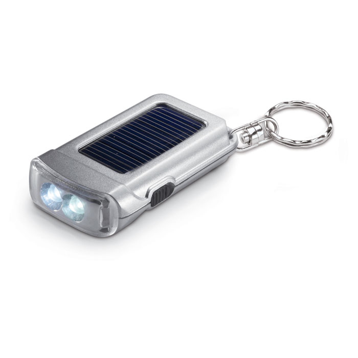 Satynowy srebrny breloczek do kluczy z latarką na baterię słoneczną. 2 białe światła LED.. Gadżet reklamowy dla firmy.